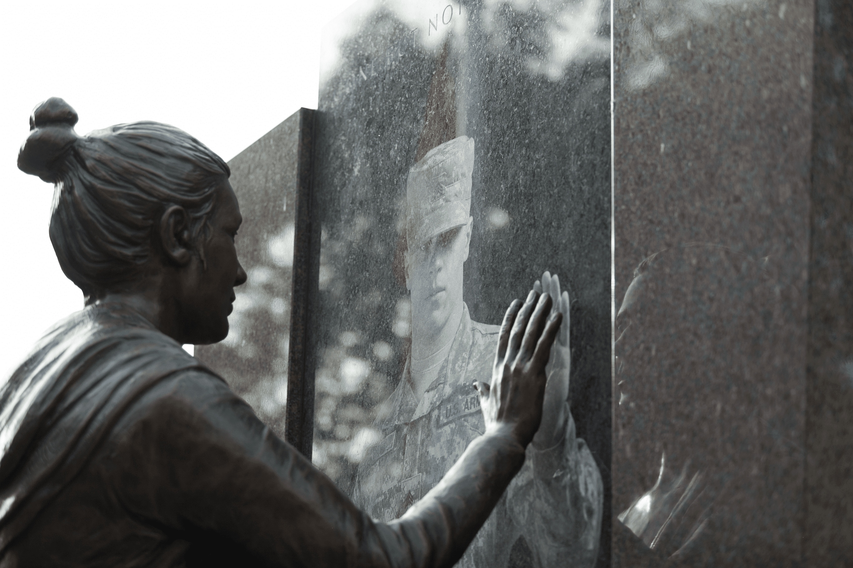 Bronze figure beside an etched portrait in polished granite